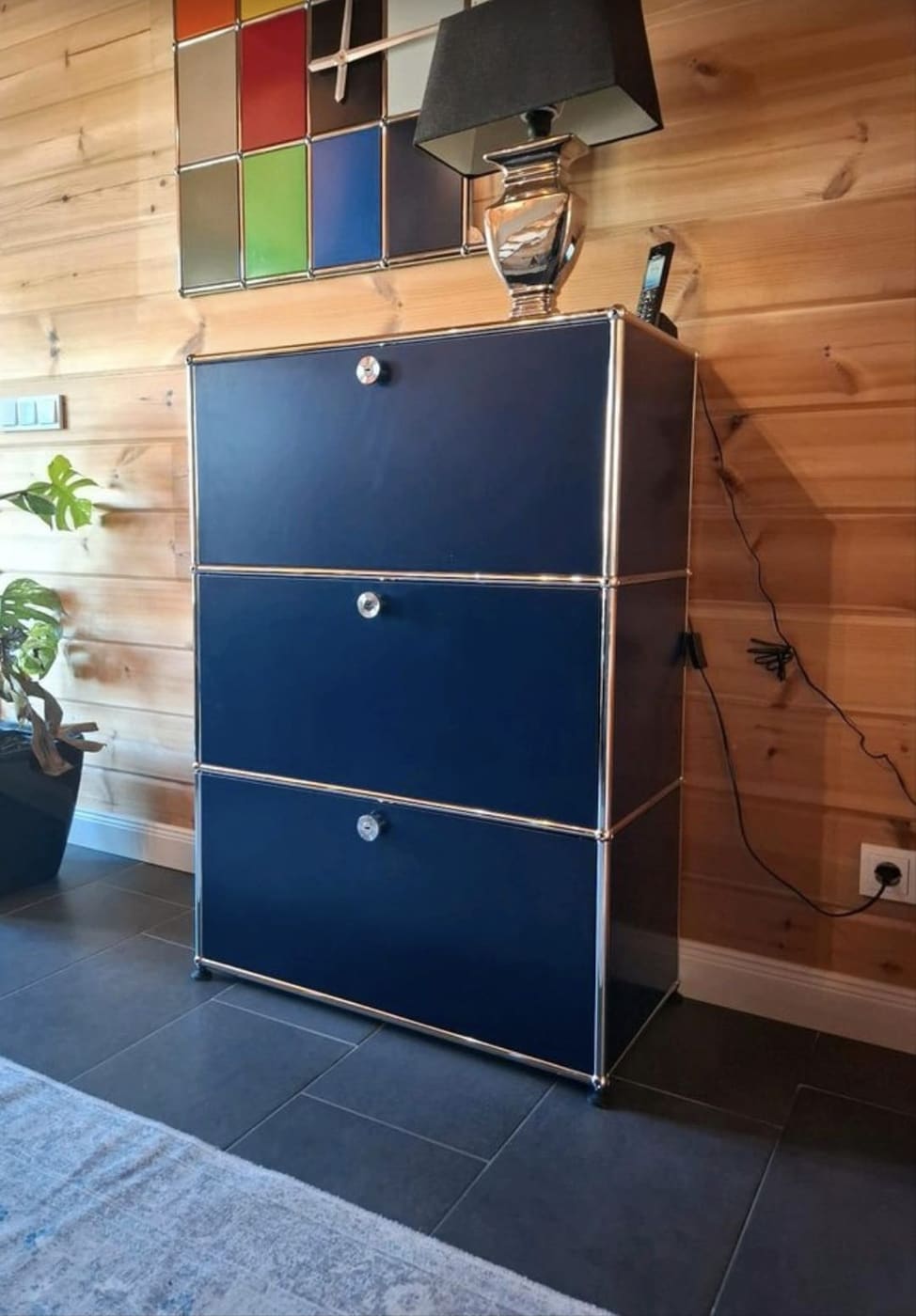 Nachtblaues Highboard mit bunter Wanduhr